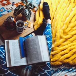 Gemütlich hochgelegte Füße auf einer Couch mit Buch und Teetasse