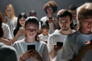 Stimmungsvolles Foto einer dicht gedrängten Gruppe in einheitlichen weißen Oberteilen, die schweigend auf ihre Smartphones blickt.