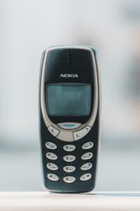 Ruhiges, nostalgisch wirkendes Foto eines klassischen Nokia-Handys mit Tastenfeld vor hellem Hintergrund.